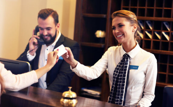 a man and a woman working at the front desk of a hotel